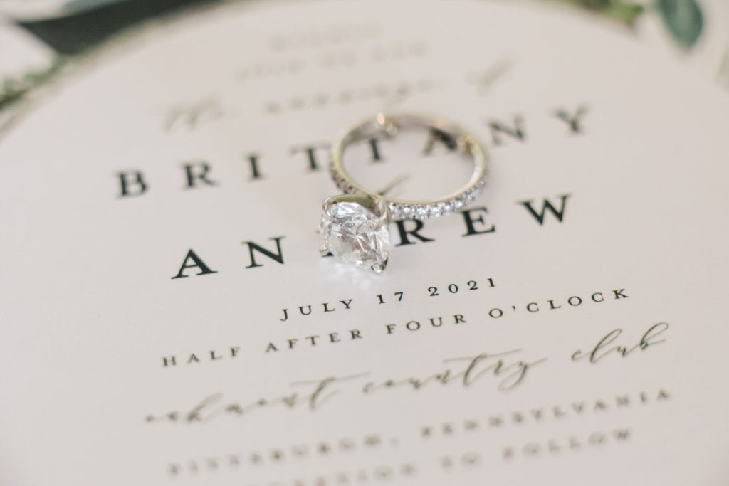 Macro photo of engagement ring laying on wedding invitation