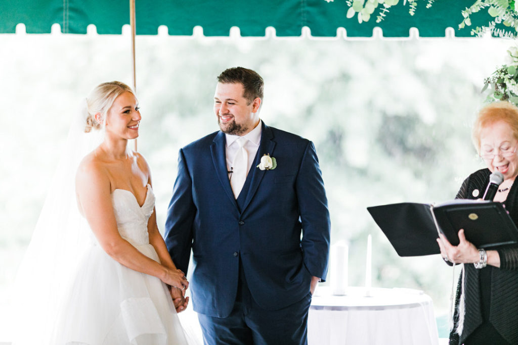 Bride and groom smile during outdoor Oakmont Country Club wedding ceremony