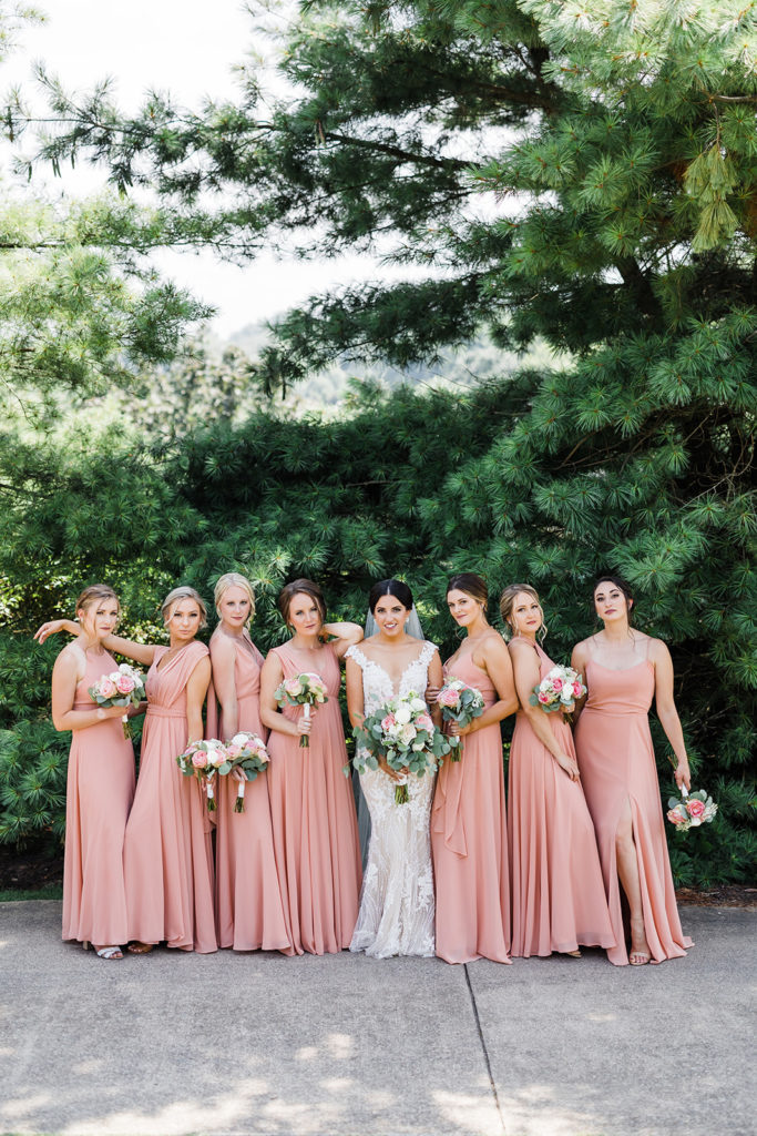 Bride poses with bridesmaids wearing full length, chiffon pink bridesmaids gowns