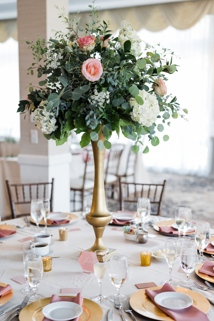Reception centerpiece featuring Gold vase topped with green, hydrangea and rose flowers 