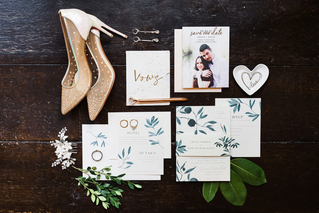 Flat lay detail photo featuring stationery, shoes, jewelry and vow book