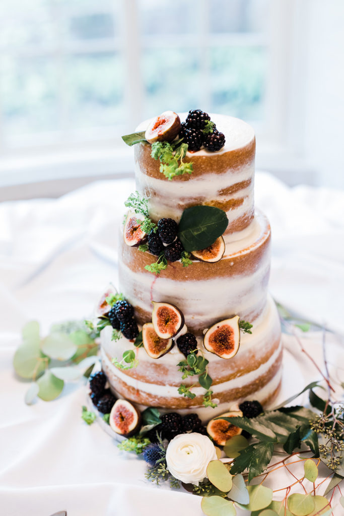 Naked wedding cake decorated in figs, berries and greens