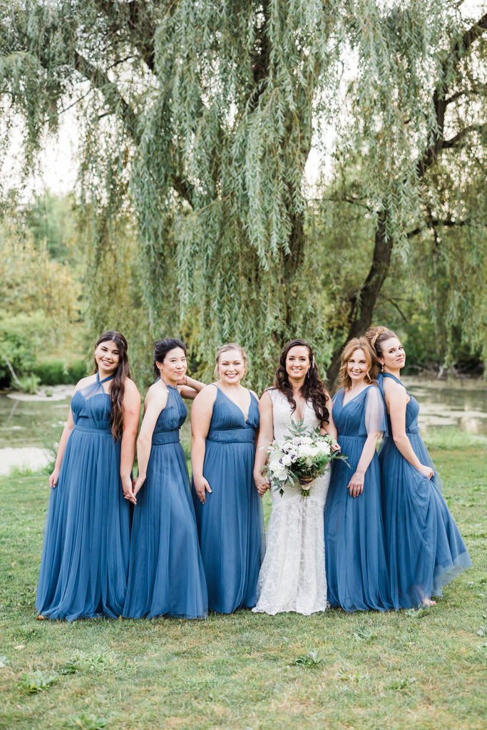 Bride and bridesmaids pose in front of willow tree at Succop Nature Park