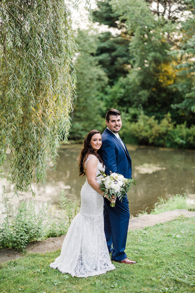 Bride and groom pose in front of lake at Succop Nature Park
