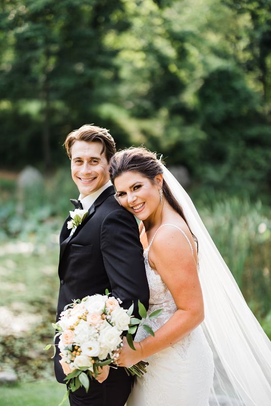 Bride and groom pose beside the lily pond at their summer Pittsburgh Botanic Garden wedding