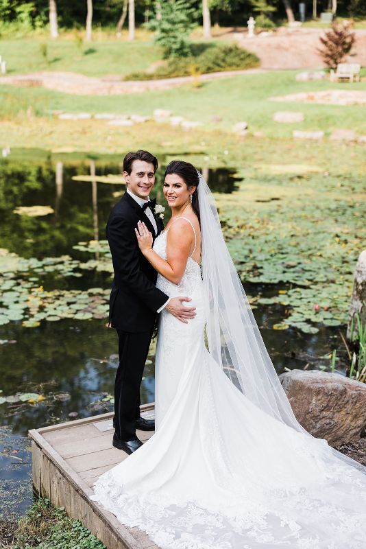 Bride and groom pose beside the lily pond at their summer Pittsburgh Botanic Garden wedding