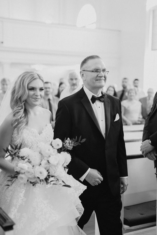 Bride smiles as father escorts her down the aisle