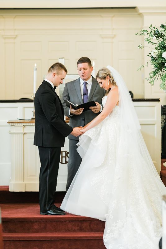 Bride and groom bow their heads and pray during their wedding reception