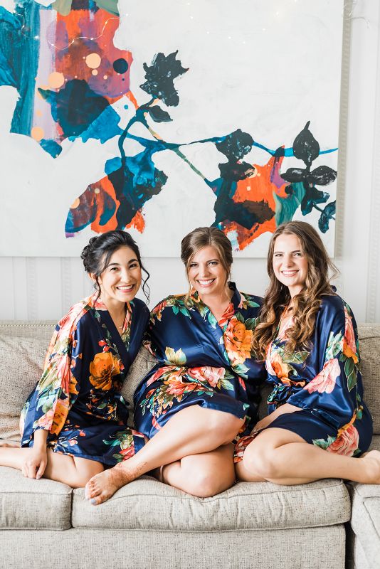 Bride and bridesmaids sit on couch with matching robes