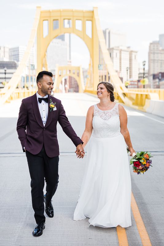 Bride and groom hold hands and walk together on the Carson Street bridge