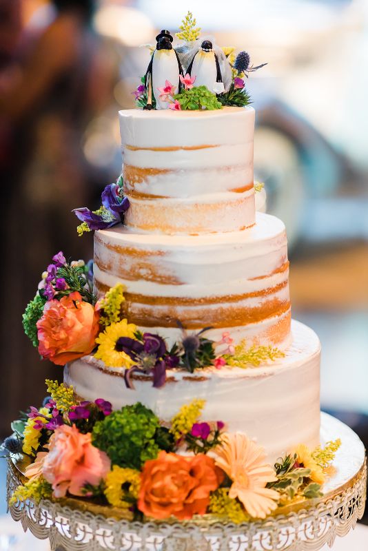 Naked cake decorated with orange, white, purple and yellow flowers