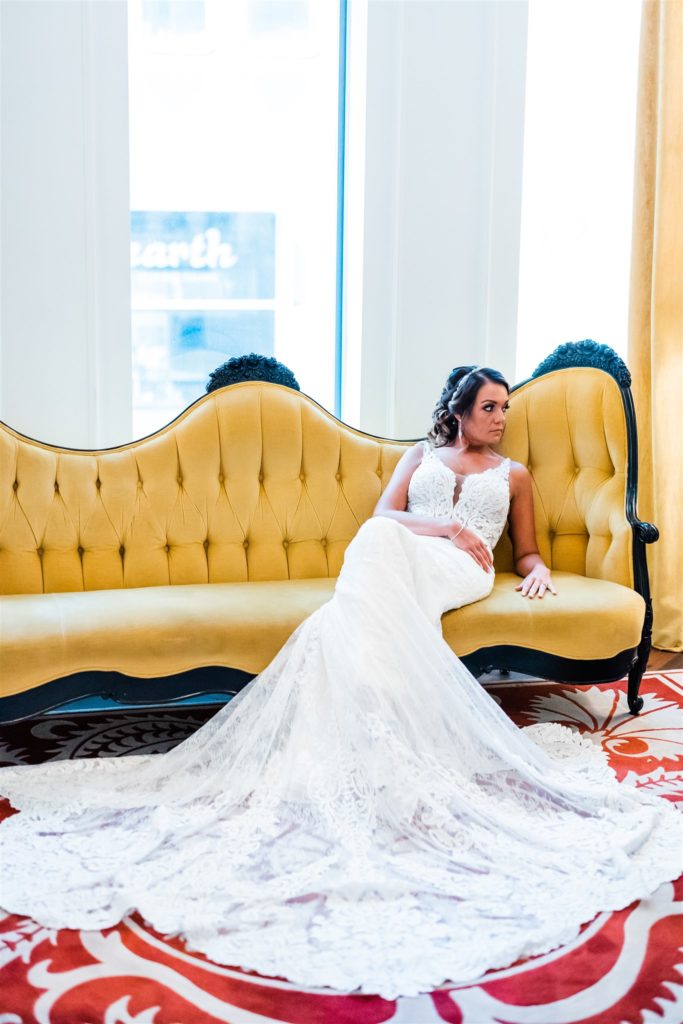 Bride relaxes on a yellow chaise couch inside the Hotel Monaco