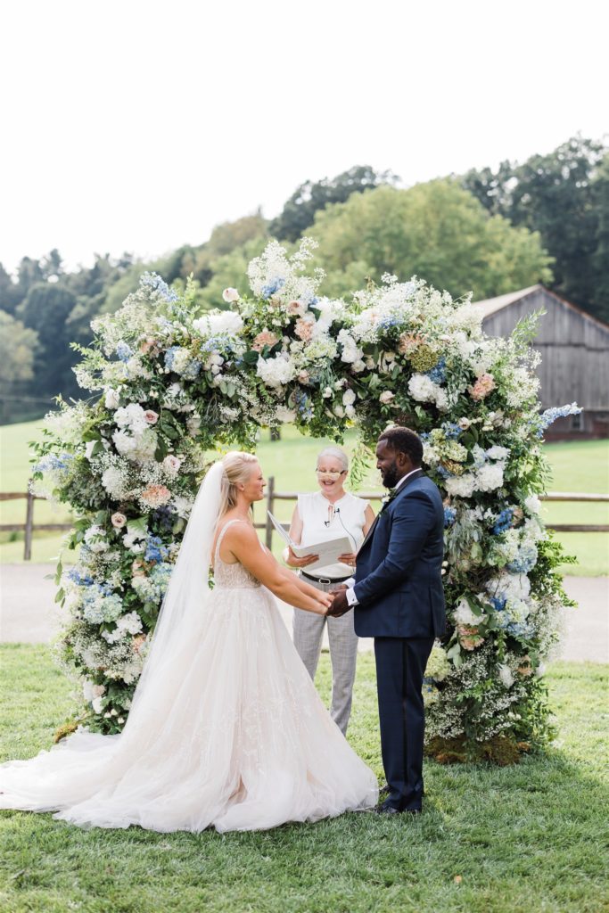 Bride and groom say their vows under floral arch