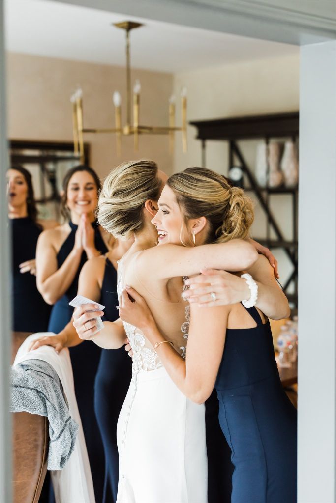 Bride and bridesmaid embrace and smile