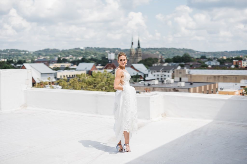 Bride stands on a scenic rooftop in her wedding attire