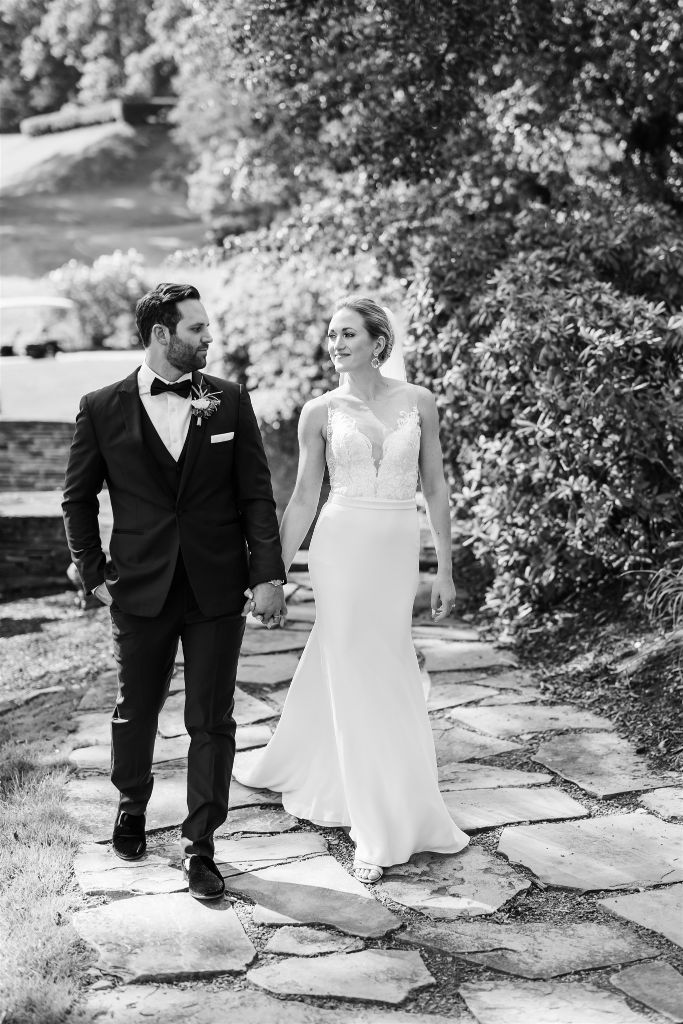 Bride and groom walk together and hold hands after their Summertime Lounge Vue Wedding ceremony