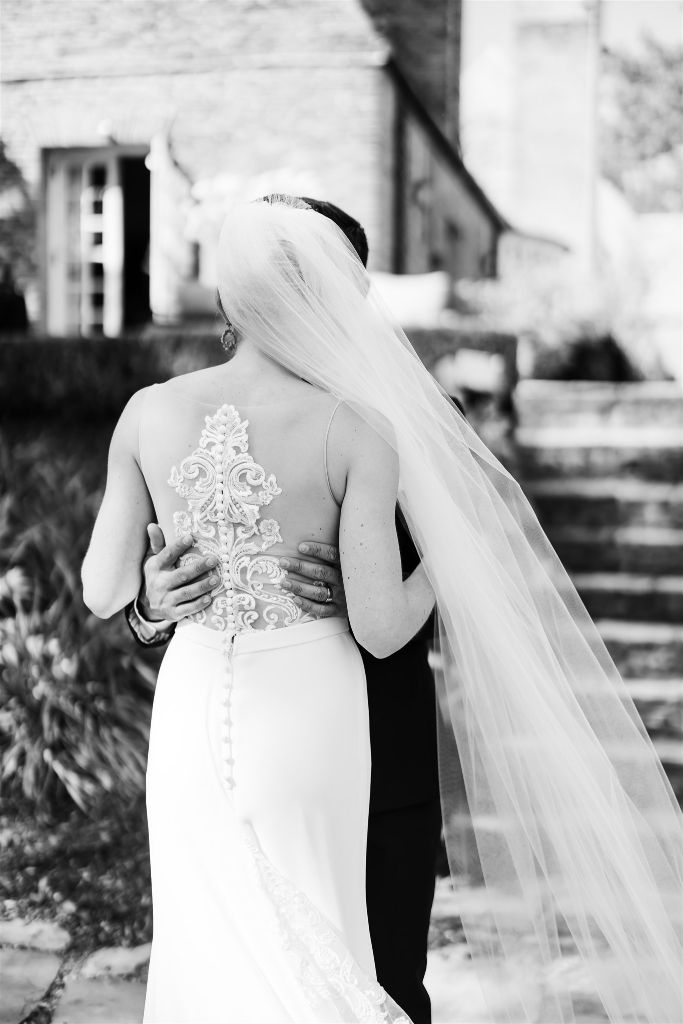 The back of the brides dress and the grooms hands holding her