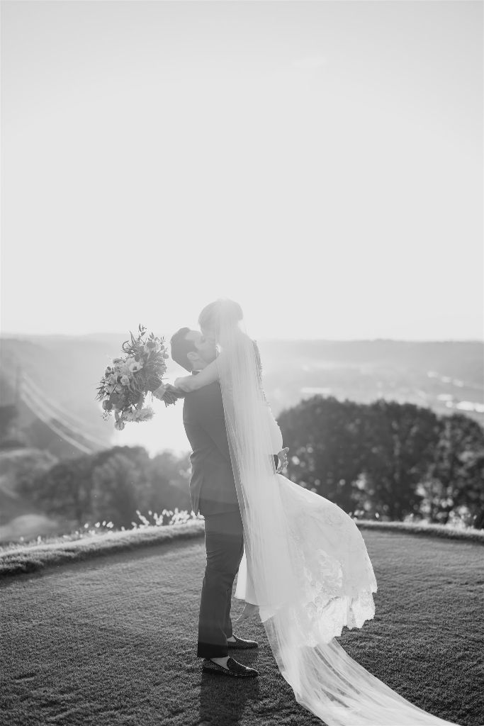 Bride and groom kiss together on the grounds of their Summertime Lounge Vue Wedding