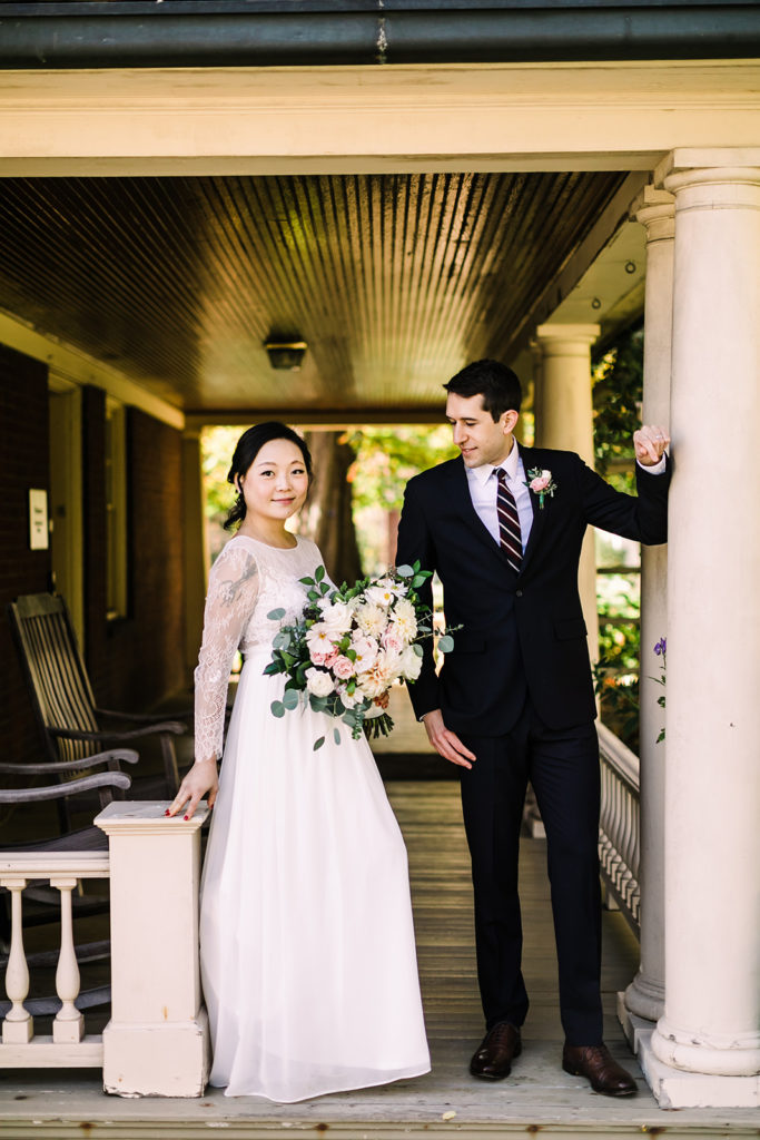 Bride and groom pose on the porch of the Frick Mansion