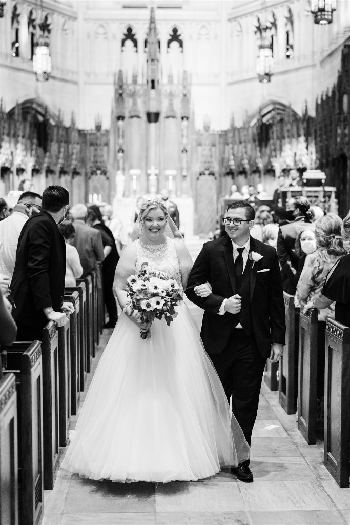 Bride and groom smile as they walk up the aisle of their classic Heinz Chapel wedding