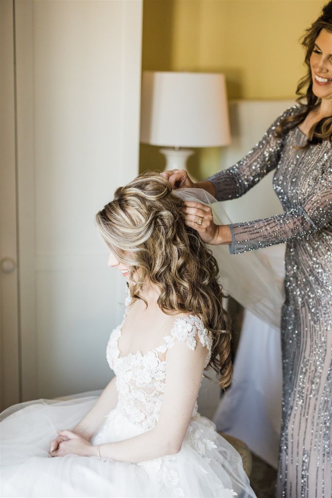 Brides mother adjusts brides hair as she helps put on her veil