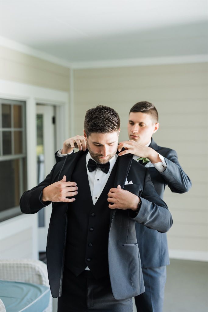 Groomsman helps the groom put on his jacket