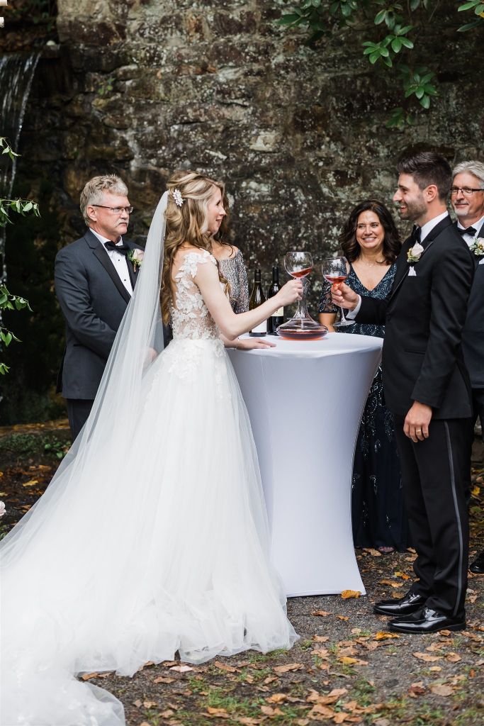 Bride and groom share glass of wine at their wedding ceremony at Bedford Springs grotto