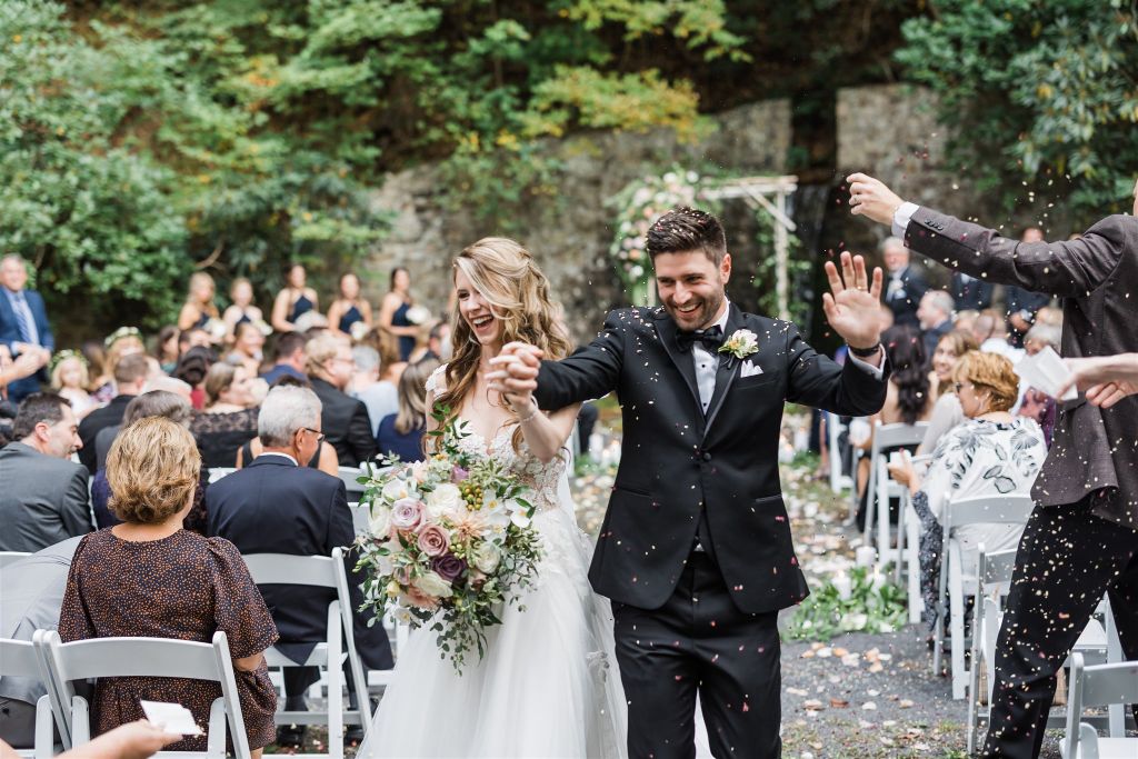 Bride and groom are showered with confetti as they walk up the aisle after their wedding at Bedford Springs grotto