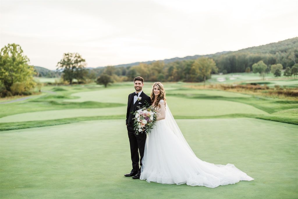 Bride and groom pose on golf course at Omni Bedford Springs