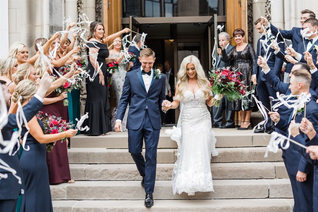 Bride and groom smile as they walk down the steps of St Paul Cathedral after their wedding ceremony