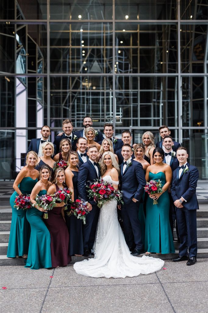 Bride and groom pose with bridal party on steps of PPG Wintergarden