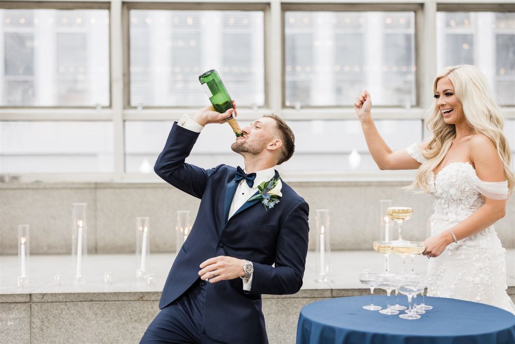 Bride cheers as groom chugs champagne 