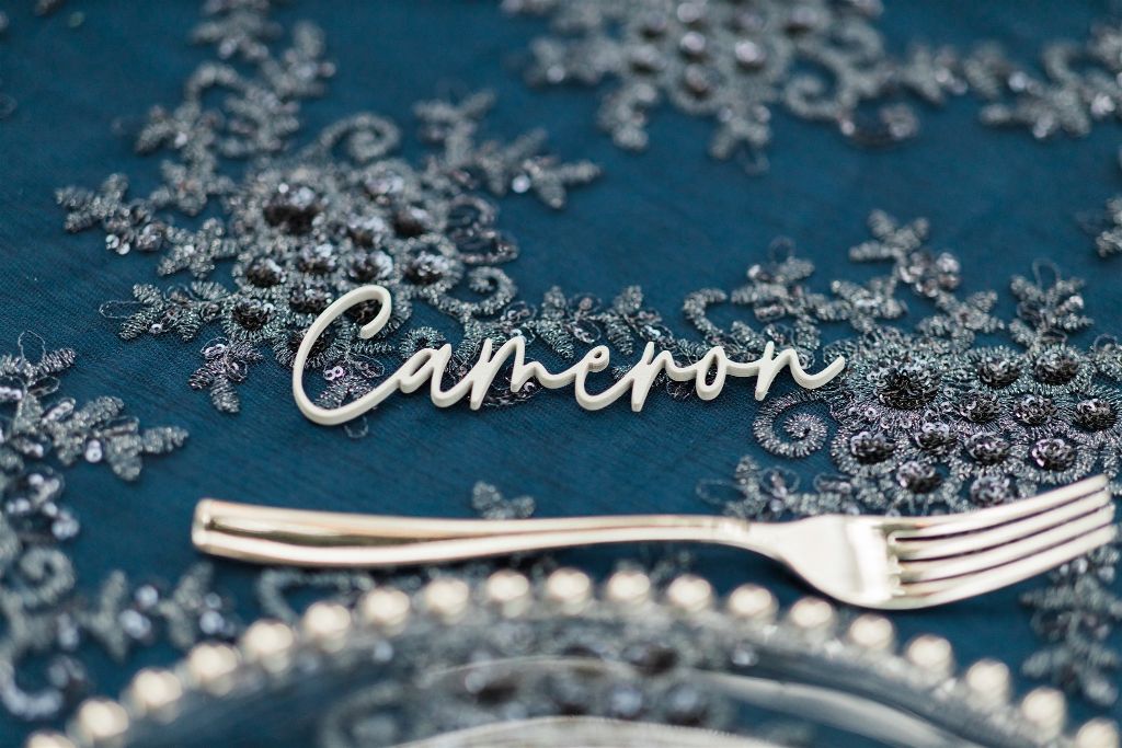 Custom calligraphy scripted place setting name on teal tablecloth