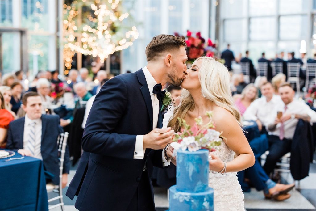 Bride and groom kiss after cutting their wedding cake at PPG Wintergarden