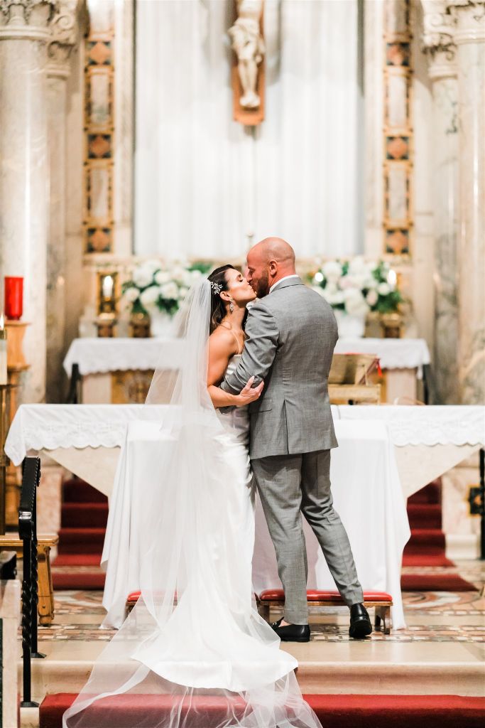 Bride and groom share first kiss at full glam downtown wedding ceremony