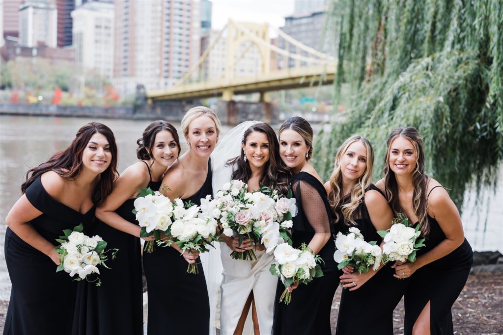 Bride and bridesmaids pose together with Roberto Clemente bridge in foreground