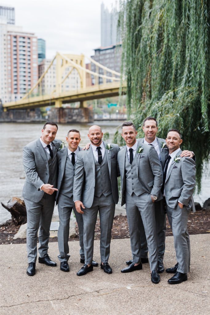 Groom smiles with groomsmen with downtown Pittsburgh in foreground