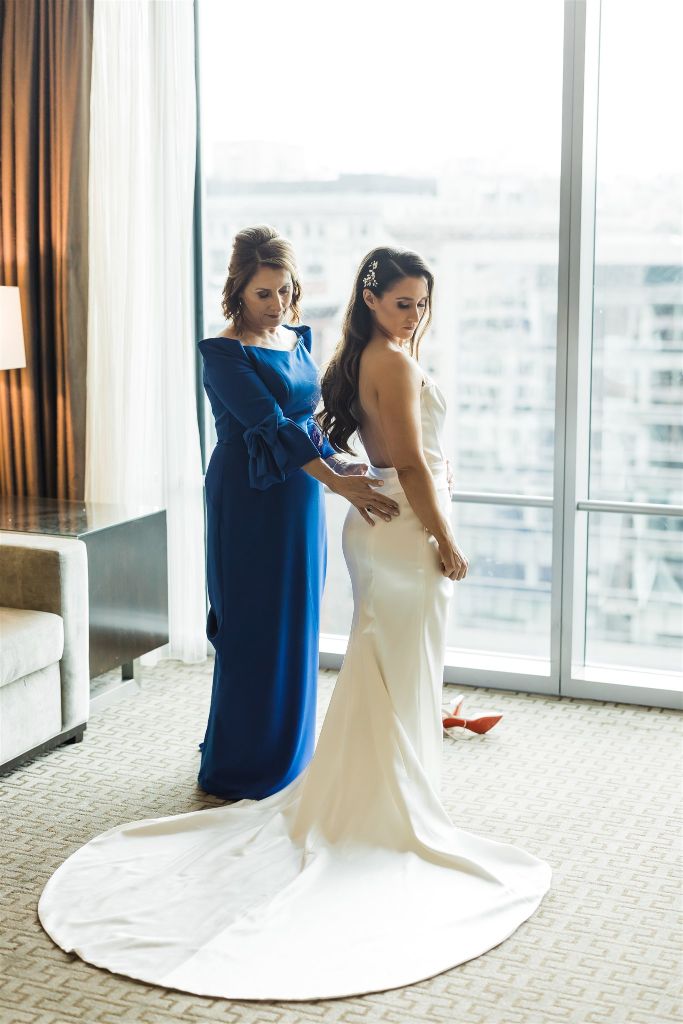 Bride and her mother adjust brides statuesque wedding gown