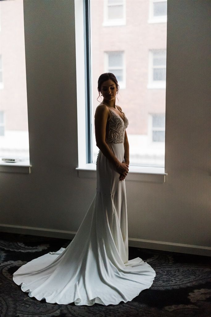 Bride poses in front of window in wedding gown