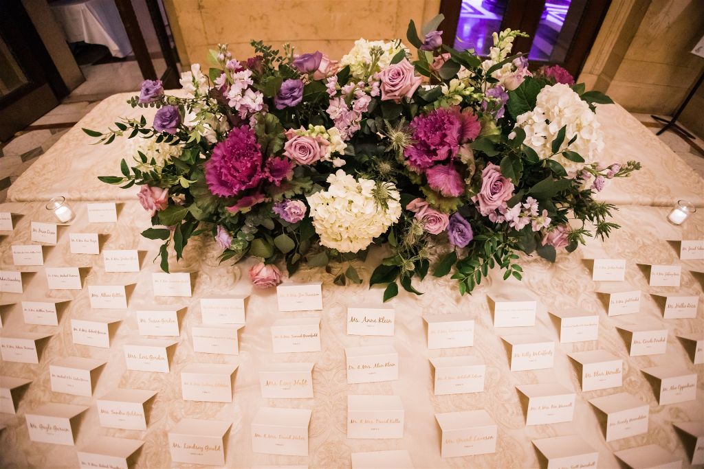 Escort card table with colorful flower arrangement 