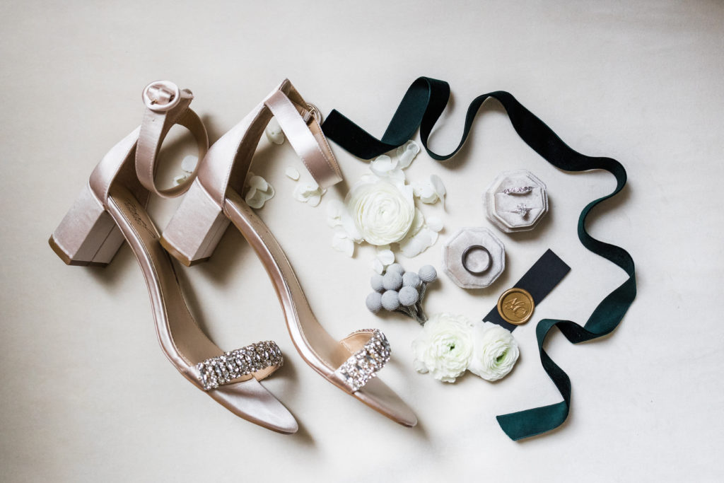 Ivory shoes, wedding rings and stationery seal in flat lay format