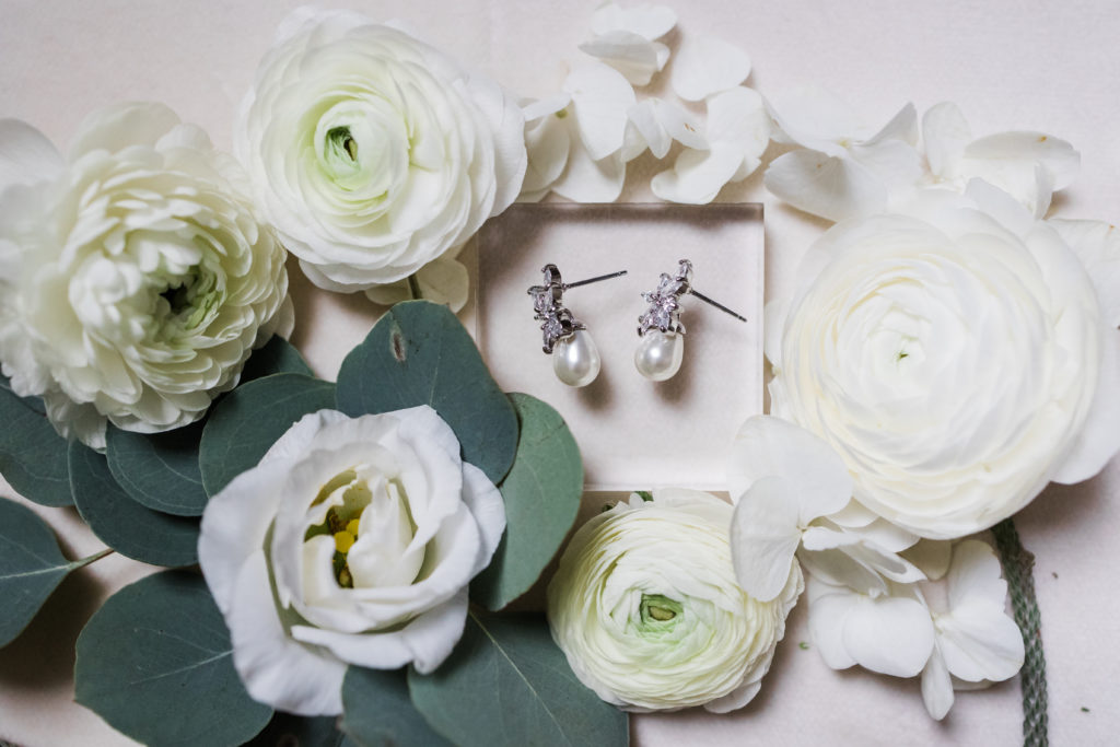 Pear earrings surrounded by ivory roses and greenery