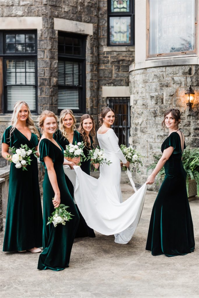 Bride and bridesmaids pose together in front of the Mansions on Fifth
