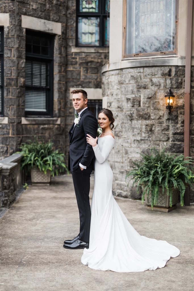 Bride and groom pose together in front of the Mansions on Fifth