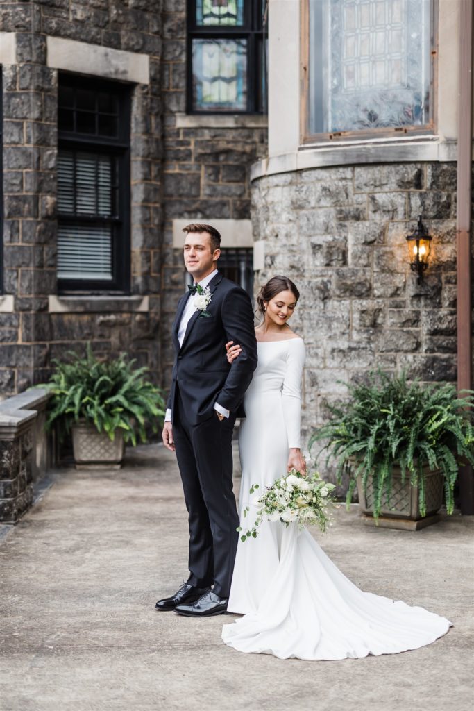 Bride and groom pose together in front of the Mansions on Fifth