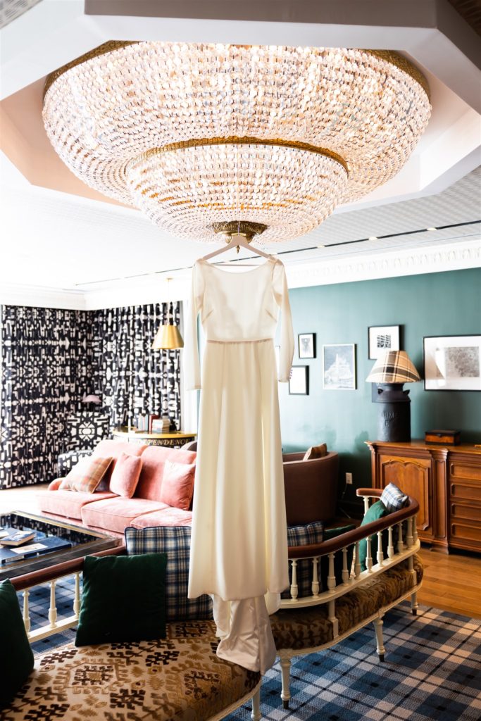 Wedding gown hanging from chandelier in a Gradute Hotel State College room
