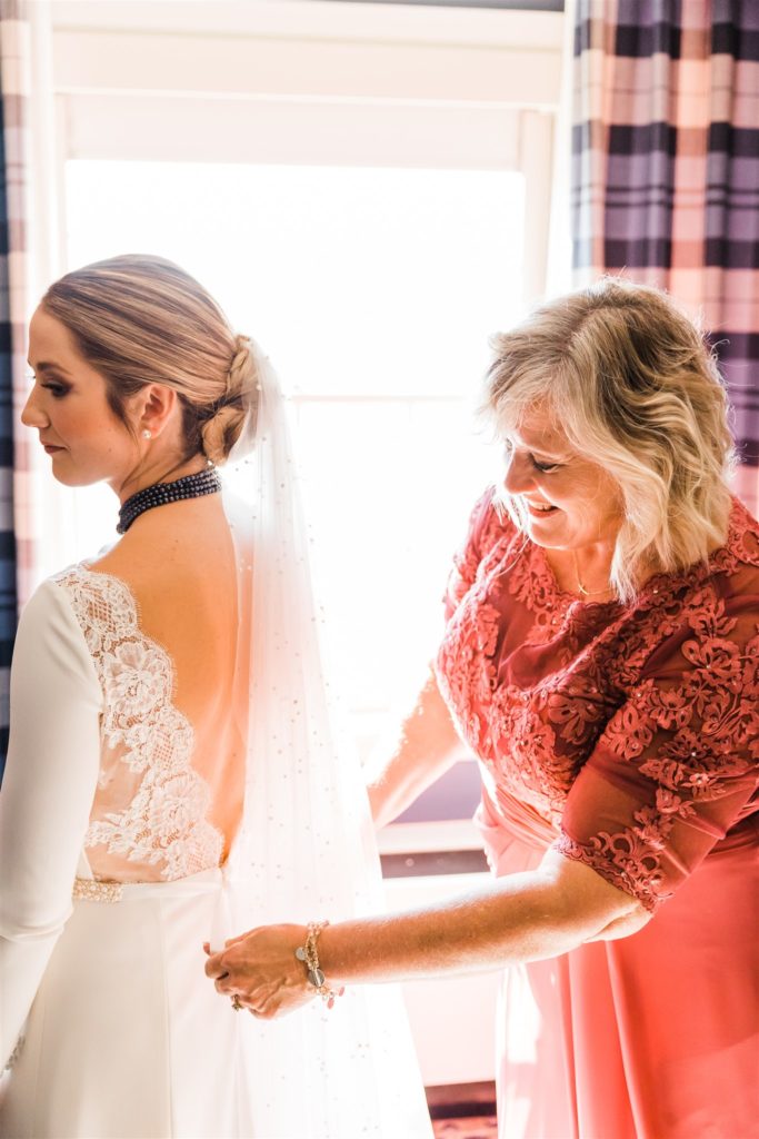 Brides mother fastens the back of her dress