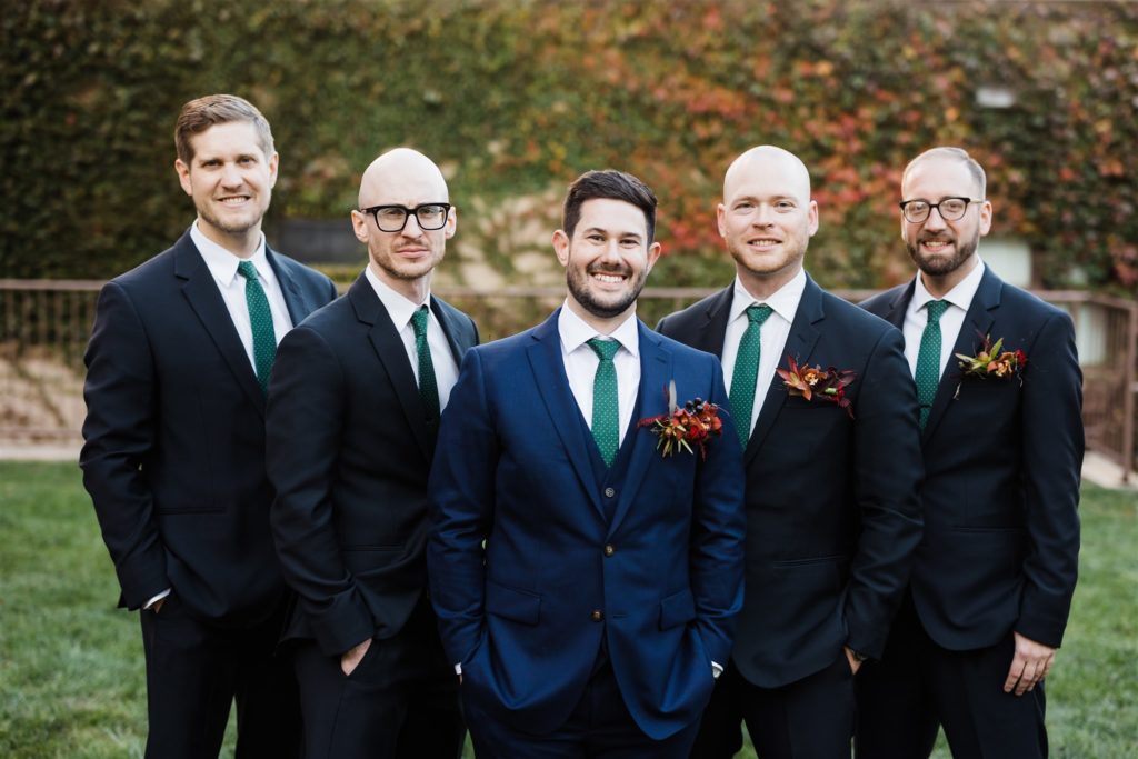 Groom and groomsmen pose outside the grounds of a Graduate Hotel fall wedding