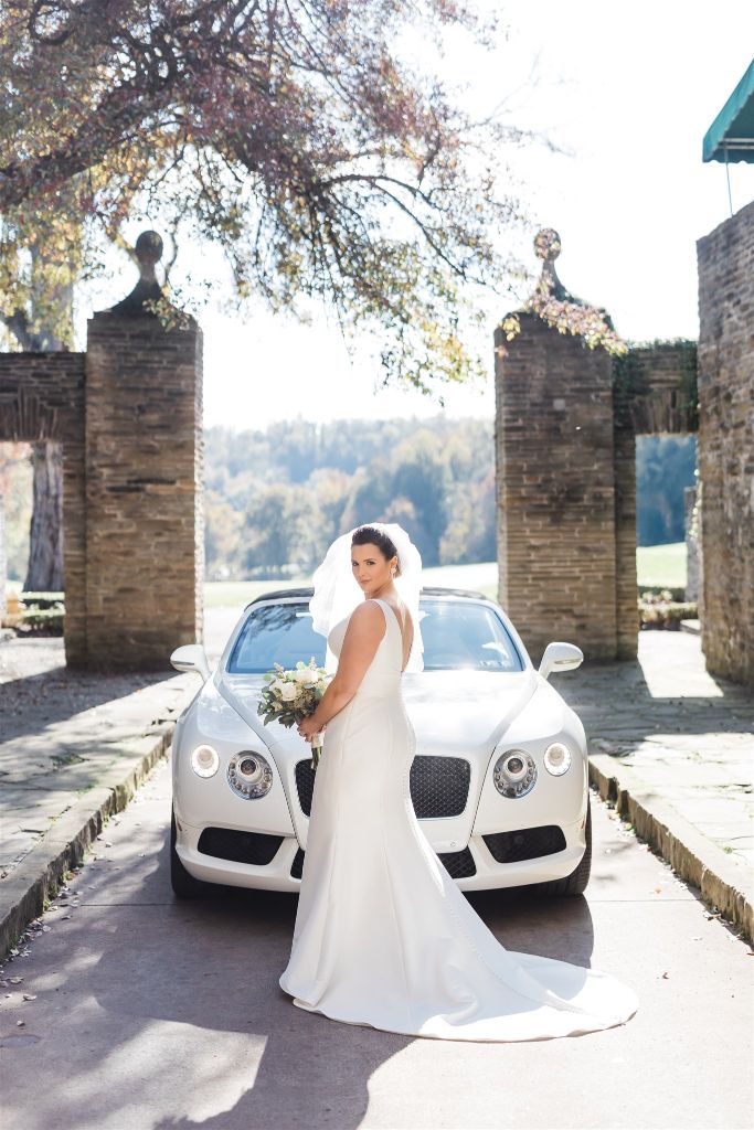 Bride poses in front of white car at Longue Vue Club