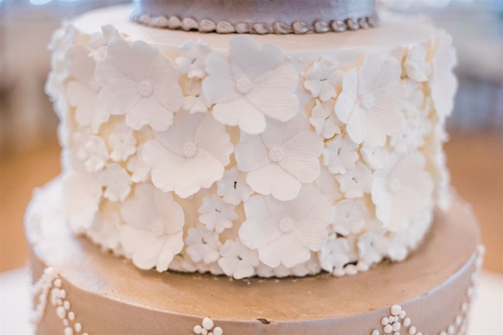 Delicate white petal flowers on white and brushed metal wedding cake